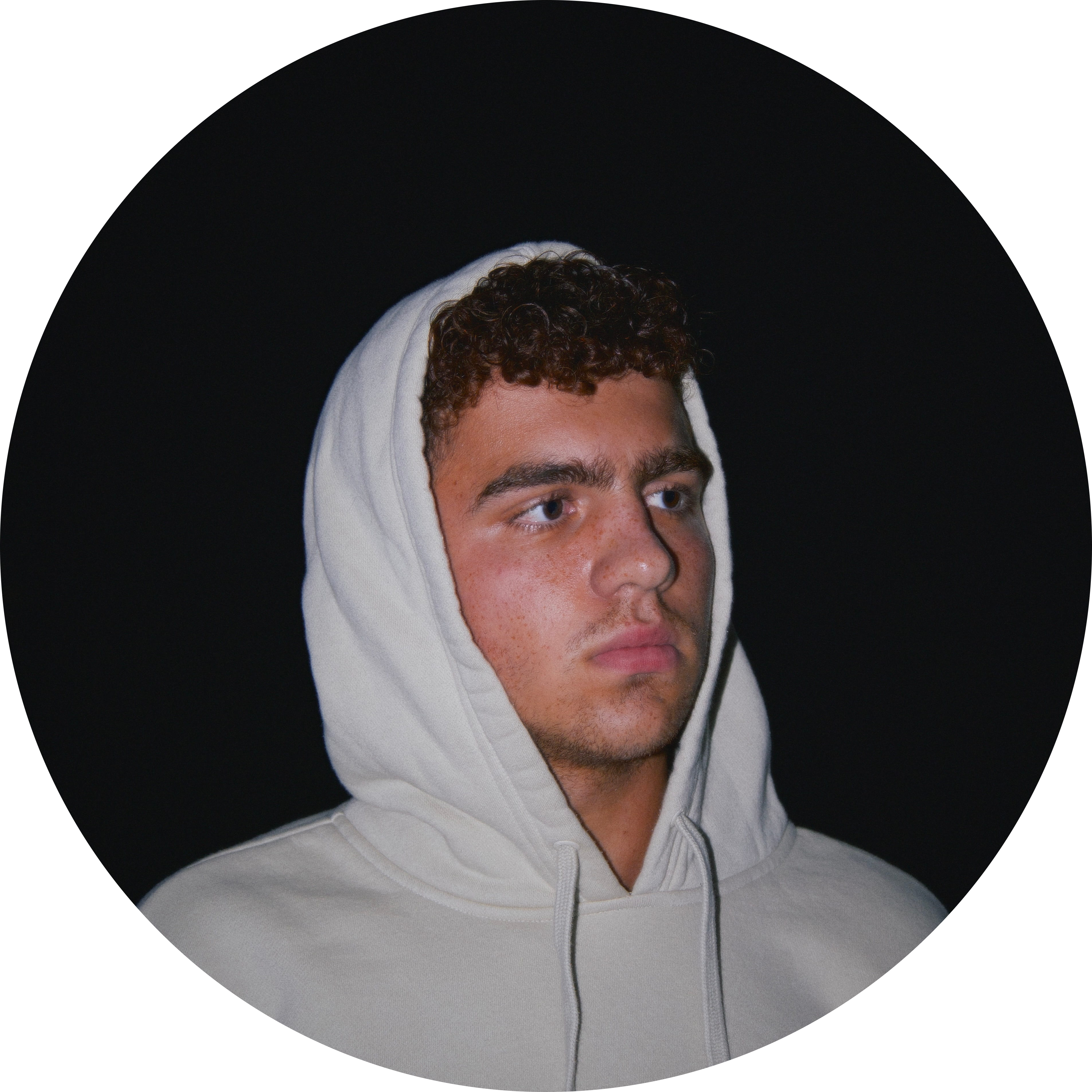 Dani wearing a light hoodie against a dark background